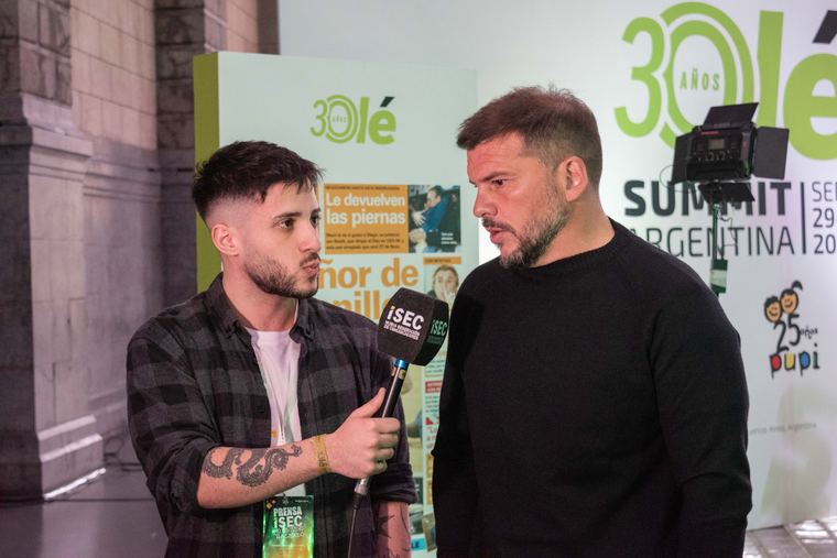 Entrevista con micrófono frente al backdrop del Olé Summit