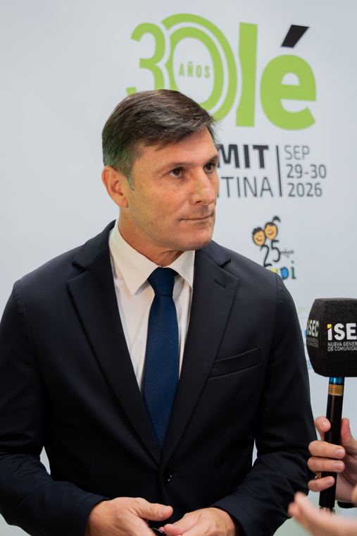 Hombre de traje respondiendo una entrevista frente al backdrop