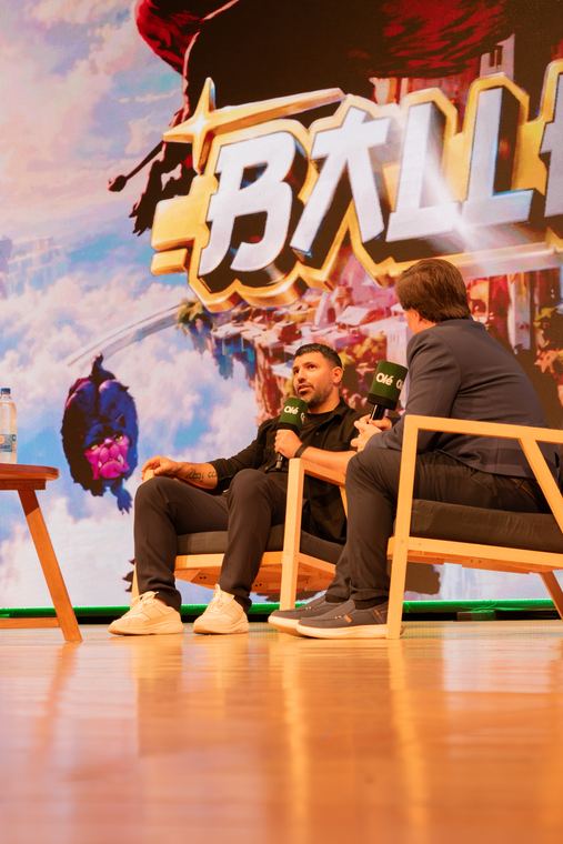 Dos personas conversando sentadas en el escenario de un panel