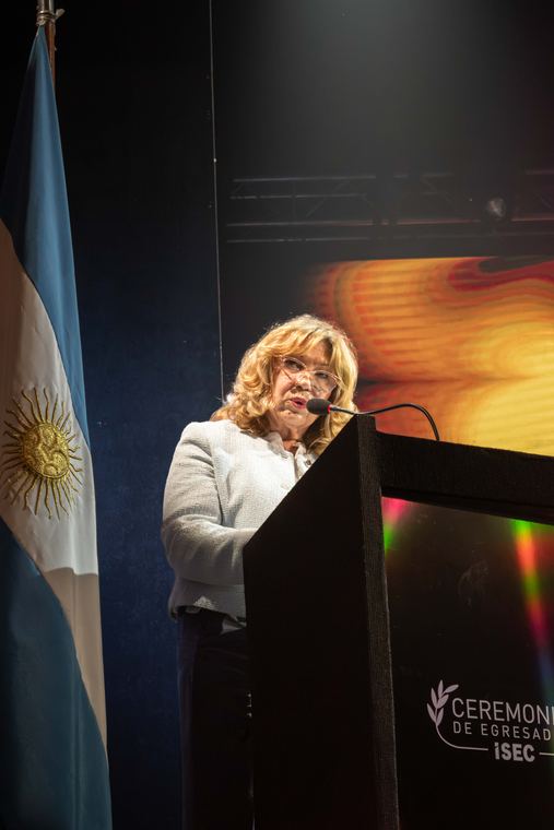 Oradora en el atril junto a la bandera argentina