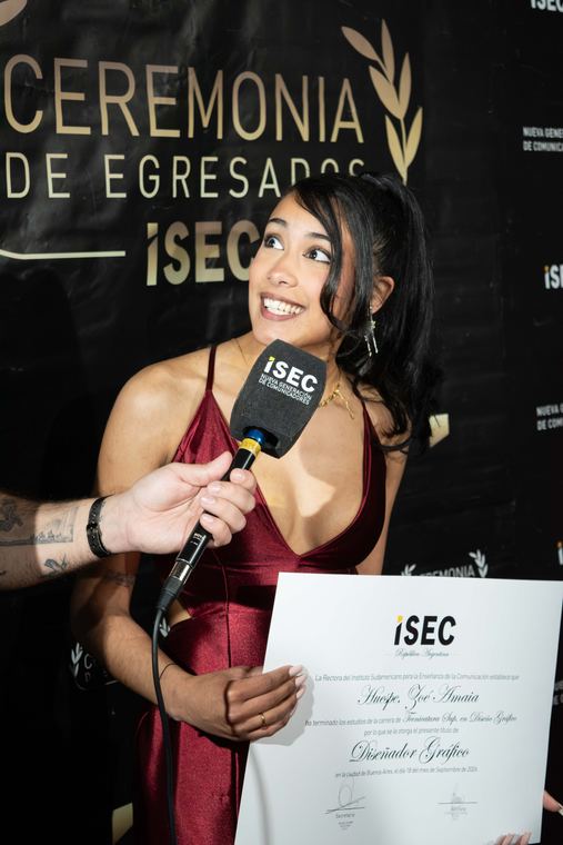 Egresada sonriendo con su diploma durante una entrevista
