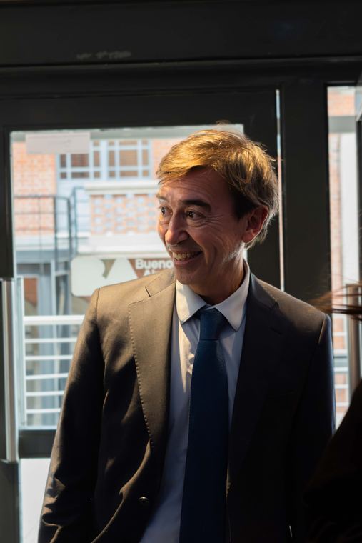 Hombre de traje conversando junto a una ventana antes del evento