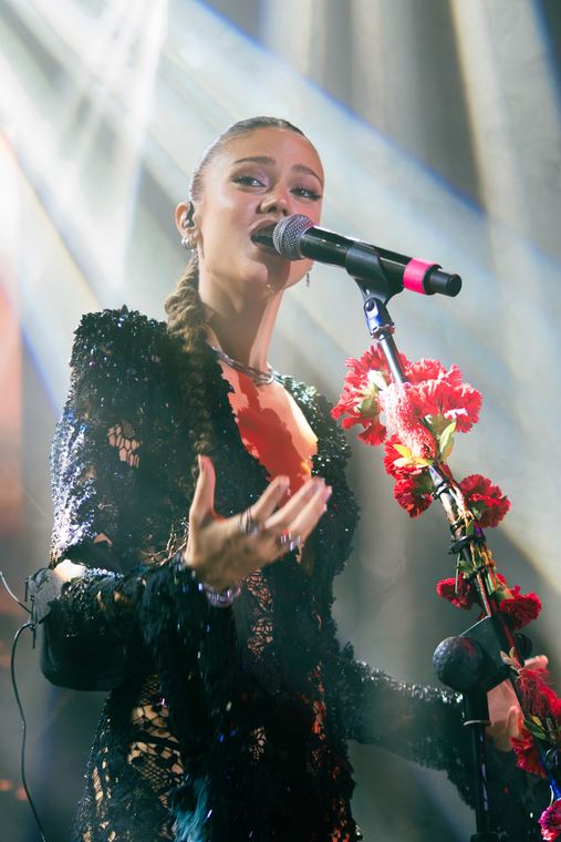 Cantante frente al micrófono con luz fría de contra