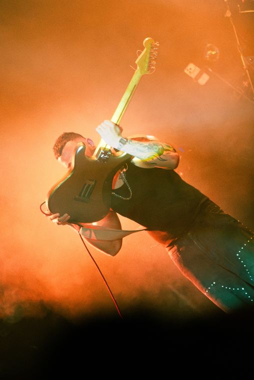 Guitarra levantada en alto entre humo naranja