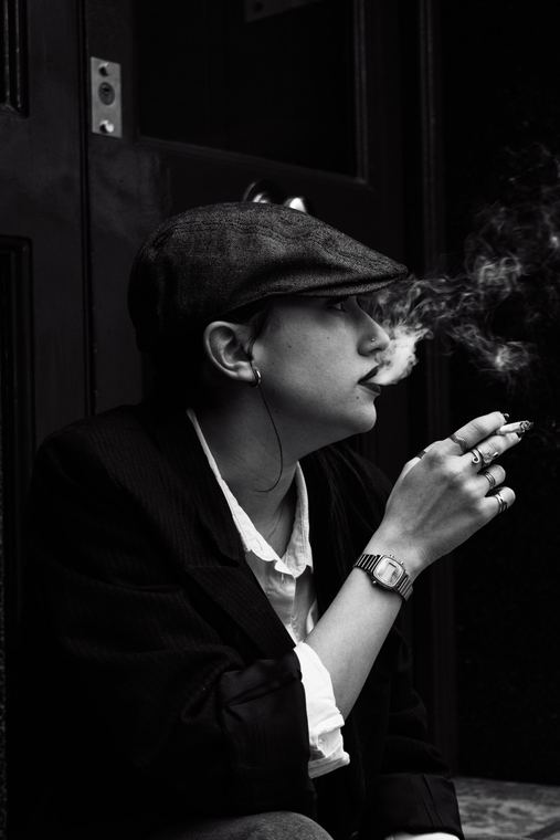 Retrato en blanco y negro de perfil, con gorra, en el umbral de una puerta