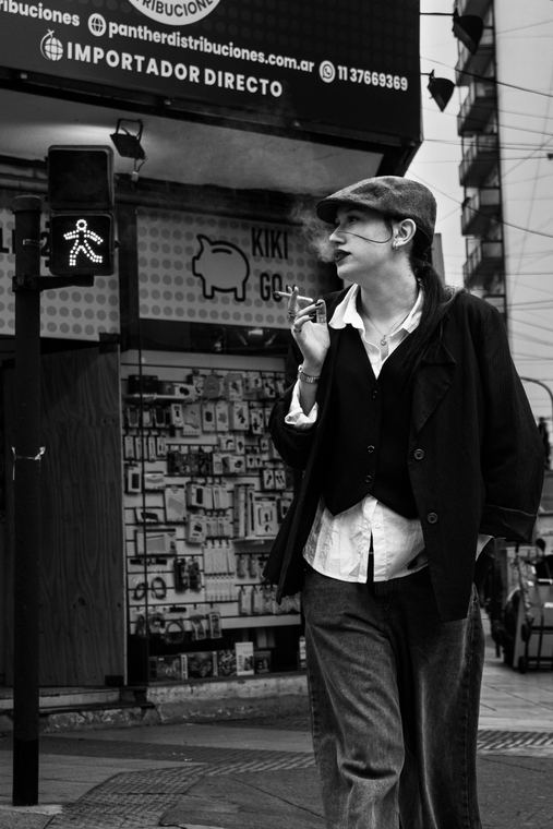 Retrato de calle en blanco y negro en una esquina, con vidriera y semáforo de fondo